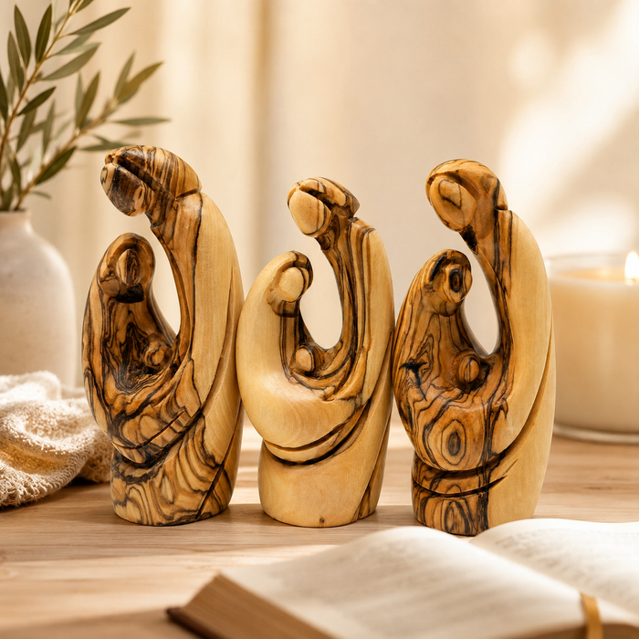 Olive wood Holy Family set of 3 on a table with a Bible and candle