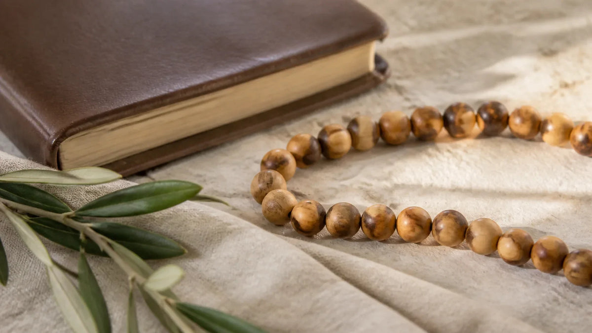 Olive wood prayer beads beside a prayer book and olive branch