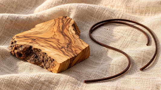 Olive wood grain and a loose dark cord resting on linen