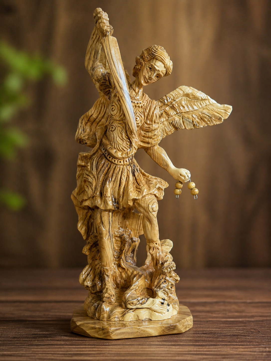 St. Michael olive wood sculpture photographed against a warm wood backdrop