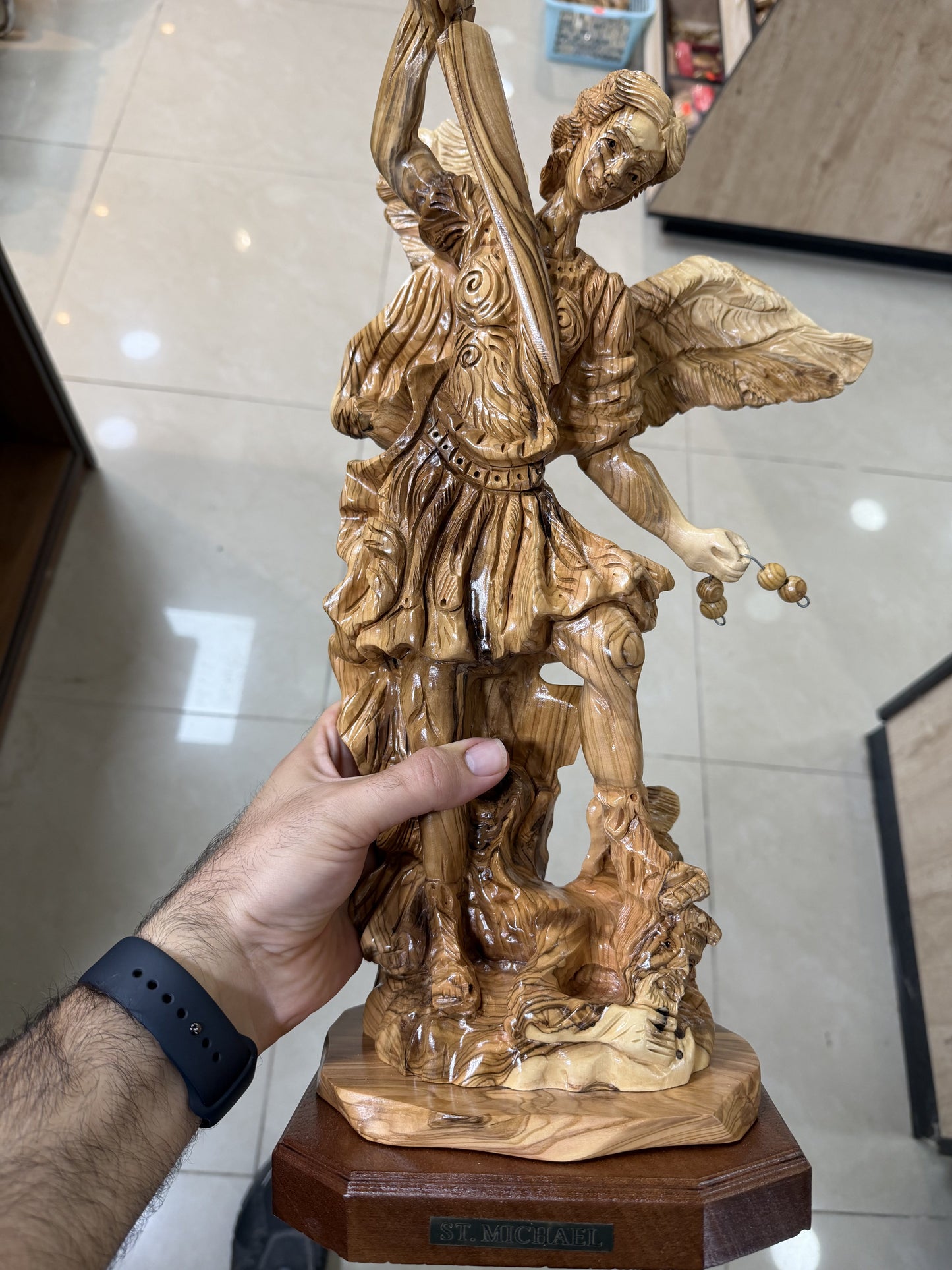 In-hand scale view of the substantial St. Michael olive wood sculpture