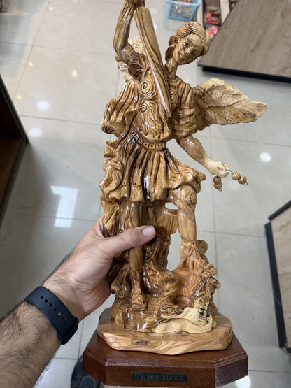 In-hand scale view of the substantial St. Michael olive wood sculpture