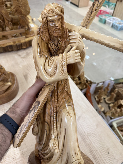 Carved hands and wooden cross detail on the Jesus carrying the cross statue