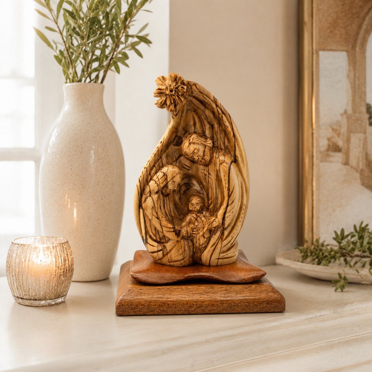 Olive wood Nativity scene on a shelf beside a candle and olive branches