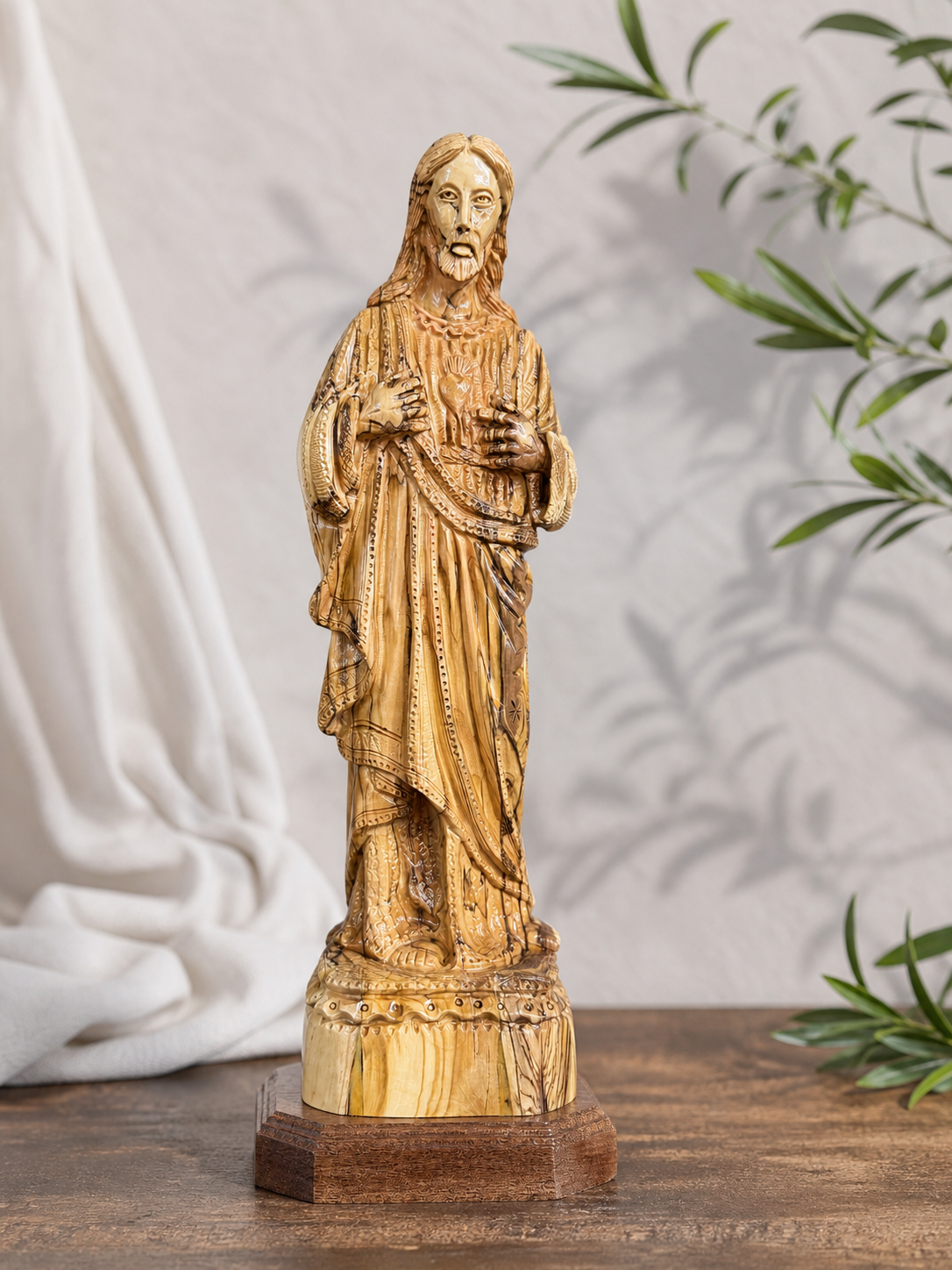 Bethlehem Sacred Heart carving shown against a soft fabric and olive branch setting