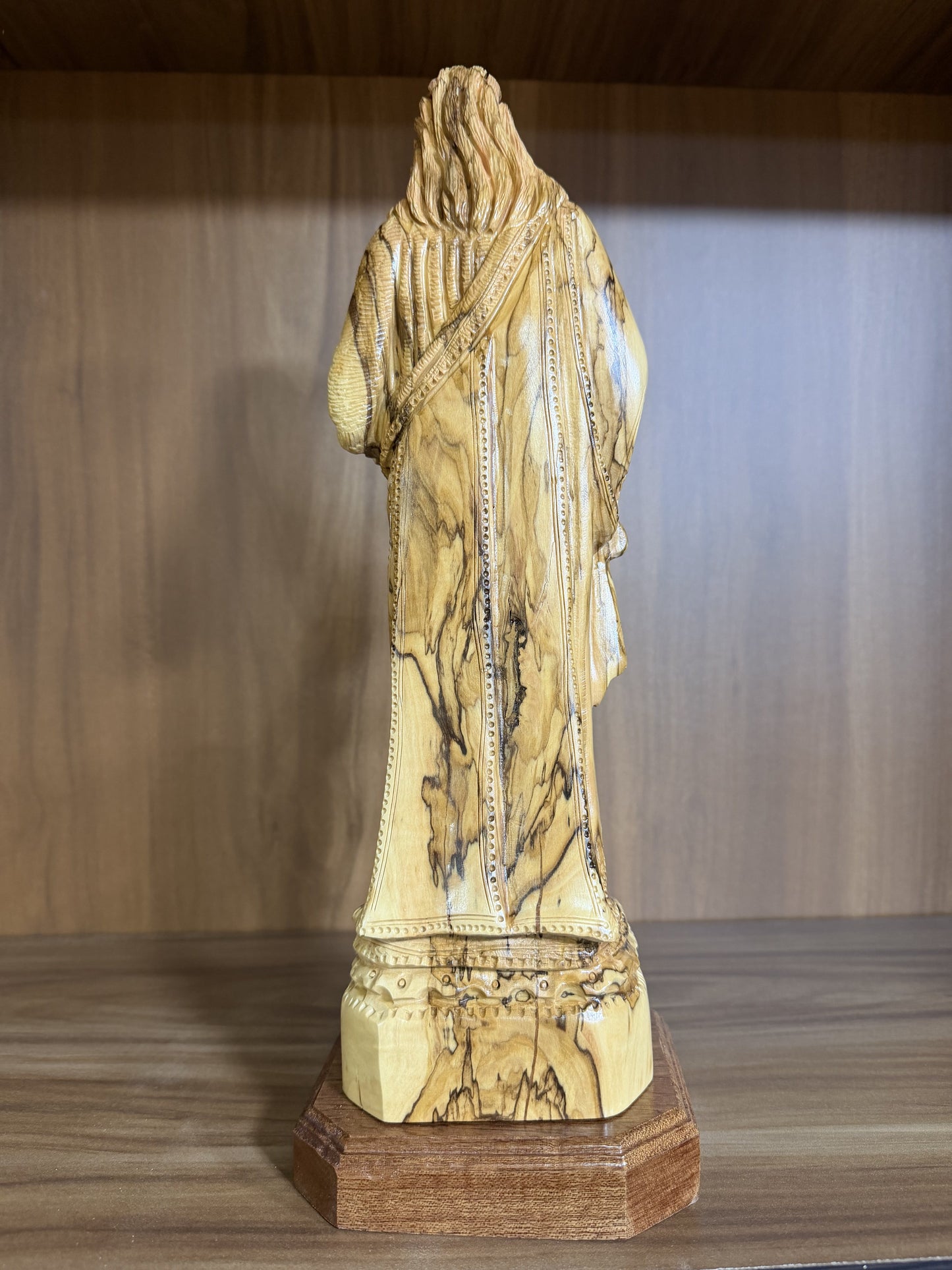 Rear view showing the robe carving and natural olive wood grain