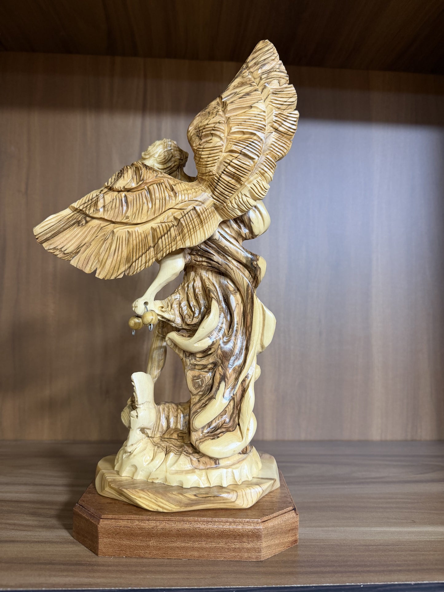 Real rear photograph of the St. Michael olive wood statue showing layered hand-carved wings