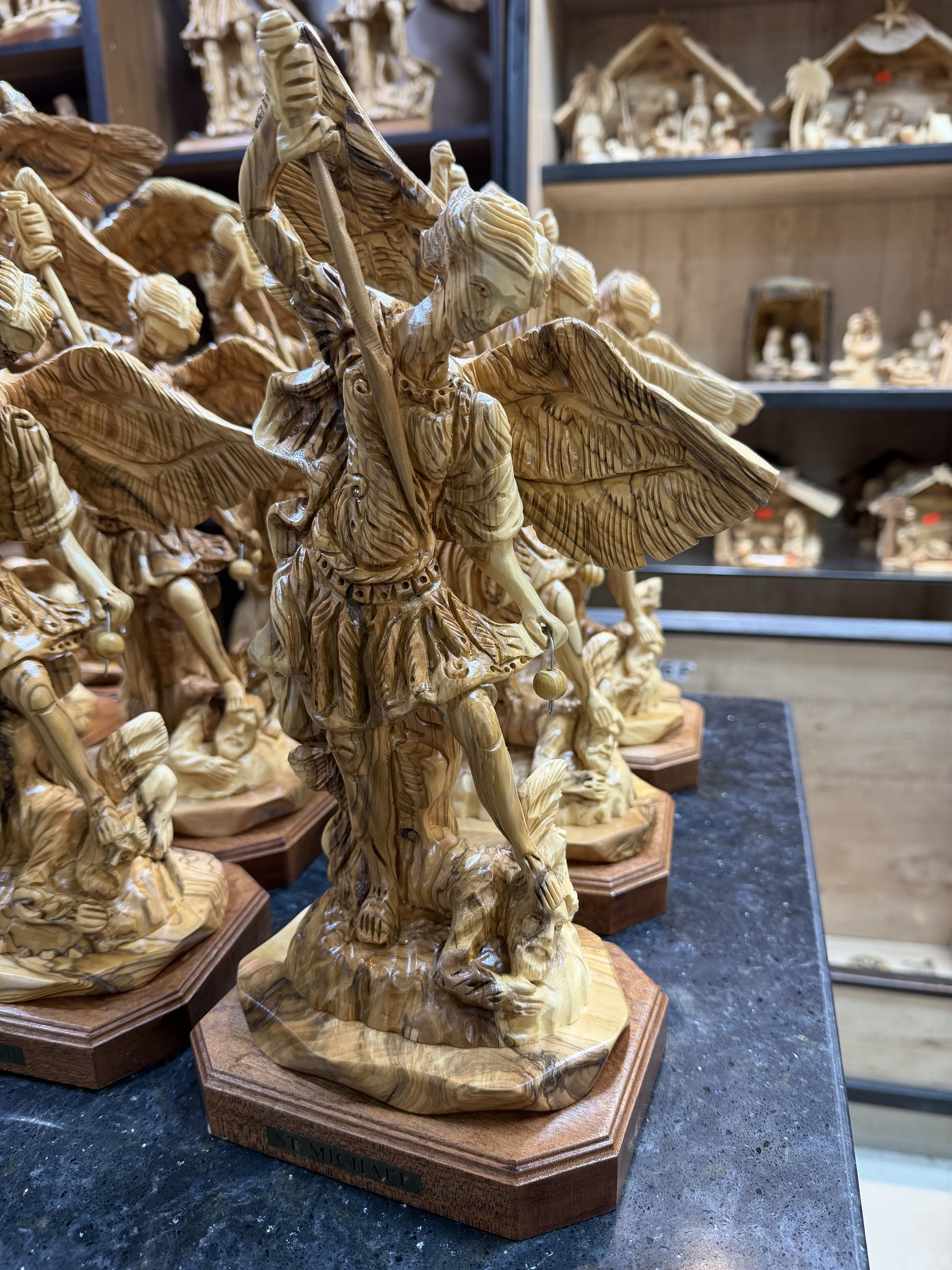 Real workshop photograph of the St. Michael olive wood statue among Bethlehem wood carvings